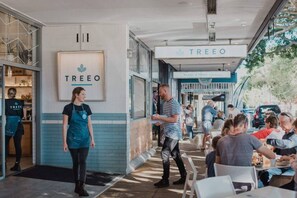 An outdoor seating area with a cafe named 'TREEO' and a person standing near the entrance.