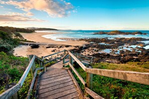 A wooden staircase leading to a beach with a view of the ocean and rocky coastline. - Endless Summer Sawtell - Luxe Beach Escape + Pool (Sawtell)