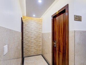 Un couloir avec une porte en bois, un mur en pierre et un panneau indiquant le deuxième étage et la rue adjacente.