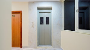 A hallway with a wooden door marked '204', an elevator, and a marble floor.