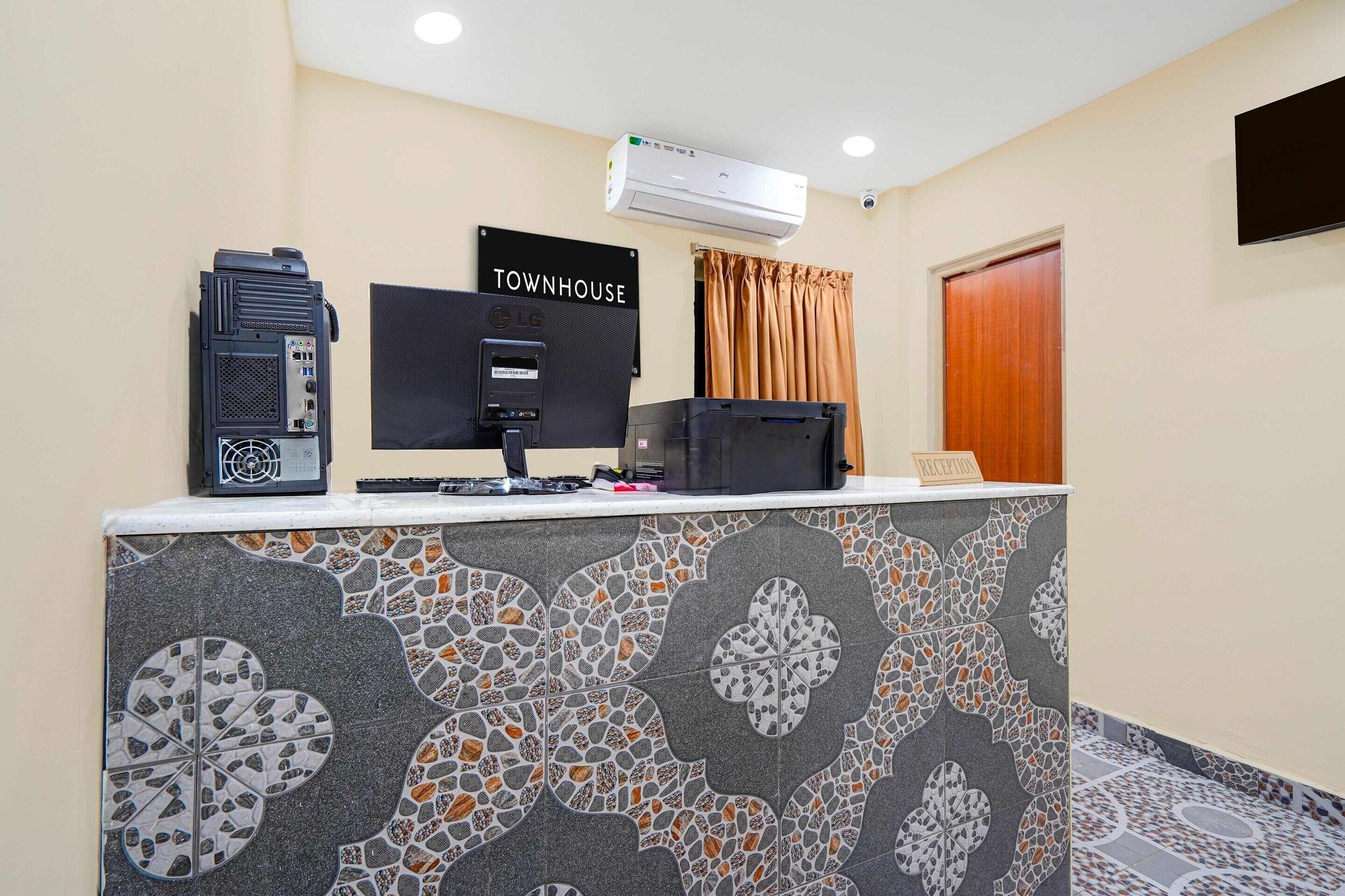 A reception desk with a monitor, a coffee machine, and a sign that reads 'TOWNHOUSE.'