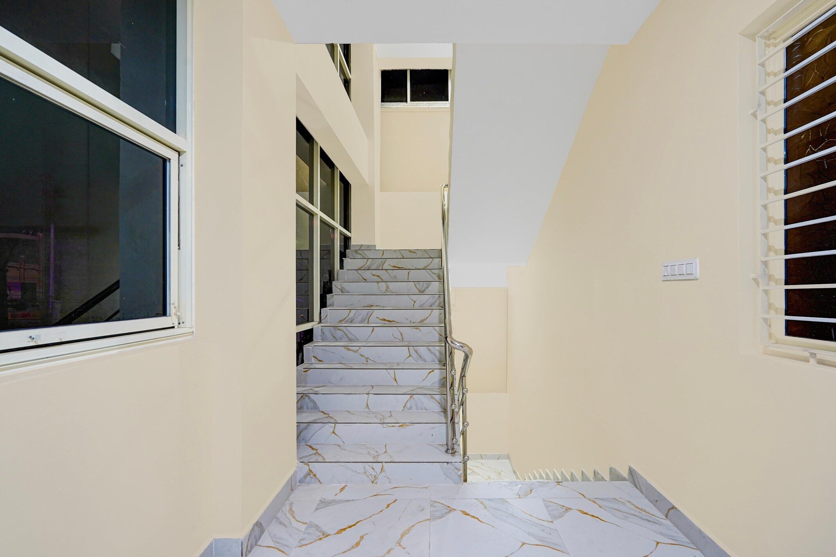 A narrow stairway with marble steps and a metal handrail, leading to an upper floor.