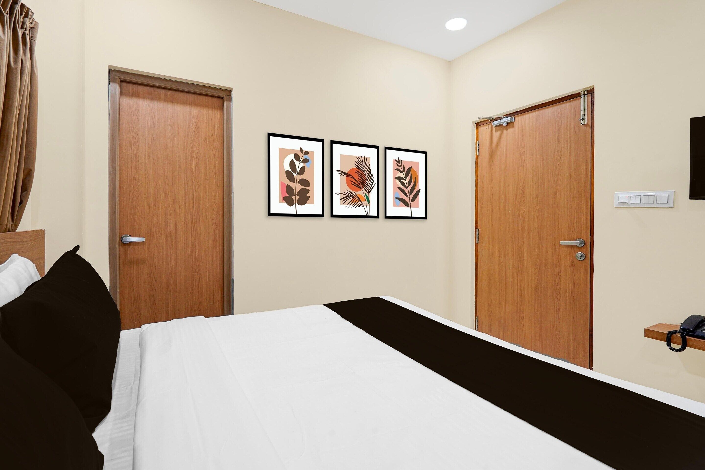 Quarto de hotel com uma cama, duas portas e três quadros na parede.