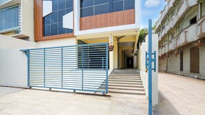 A modern building with a blue gate, a staircase leading to a door, and a paved courtyard.