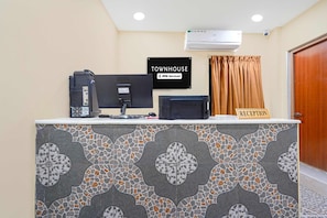 A reception desk with a sign reading 'TOWNHOUSE' and 'RECEPTION,' a computer, a printer, and an air conditioning unit mounted on the wall. - Collection Chittinagar Formerl Residency (Vijayawada)