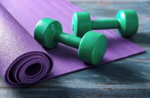 A purple yoga mat and two green dumbbells on a wooden surface. - Oceanfront 2BR/2BA Home · 2 Kings, Fast WiFi, AC, BBQ & Fire Pit (Ewa Beach)