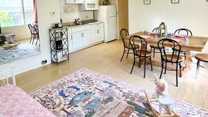 Un'ampia zona giorno con tavolo da pranzo, sedie, divano e angolo cottura completo di mobili ed elettrodomestici.