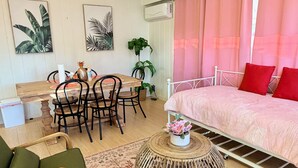 Una stanza con un letto, un tavolo da pranzo con sedie, un tavolino rotondo in vimini e un tappeto decorato.
