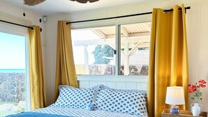 Camera da letto con un letto, una ventola a soffitto, una finestra con tende, un comodino con lampada e un tappeto.