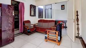 A living room with a sofa, chairs, a refrigerator, a ceiling fan, and a window.
