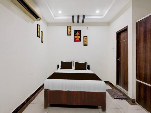 A bedroom with a bed, a wooden wardrobe, and a ceiling fan.