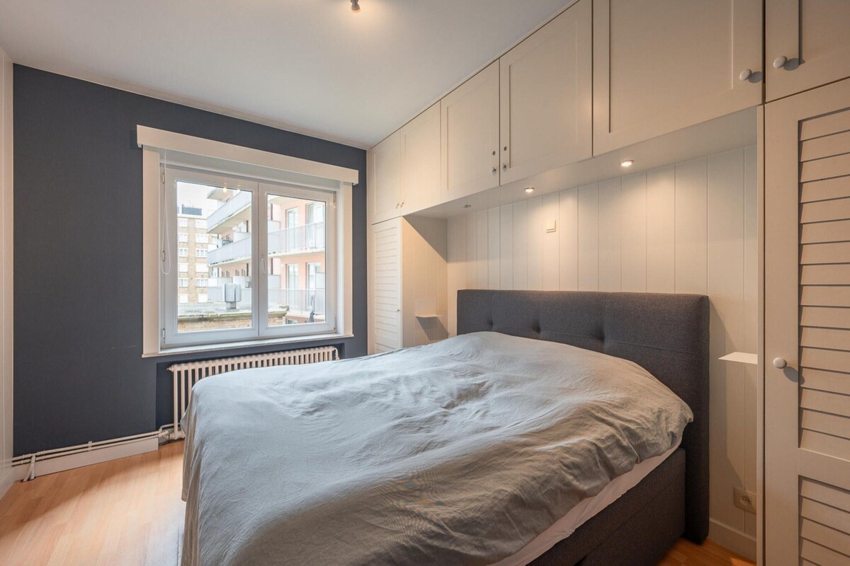 Quarto com cama, janela e armários embutidos.