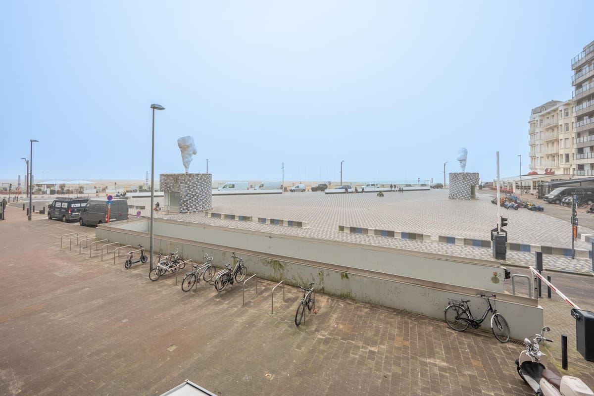 Ein Parkplatz mit Fahrrädern, einer Statue und einem Gebäude im Hintergrund.