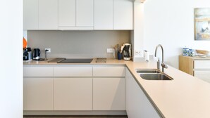 A modern kitchen with white cabinets, a stainless steel sink, and a coffee maker. - Cozy Knokke Beach Escape (Knokke-Heist)
