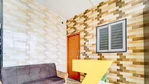 Ein Zimmer mit grauem Sofa, einer Holztür und einer Wand mit einem Pixelmuster.