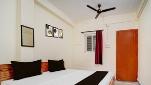 Ein Schlafzimmer mit einem Bett, einem Deckenventilator, einem Fenster mit Vorhängen und einer Tür.