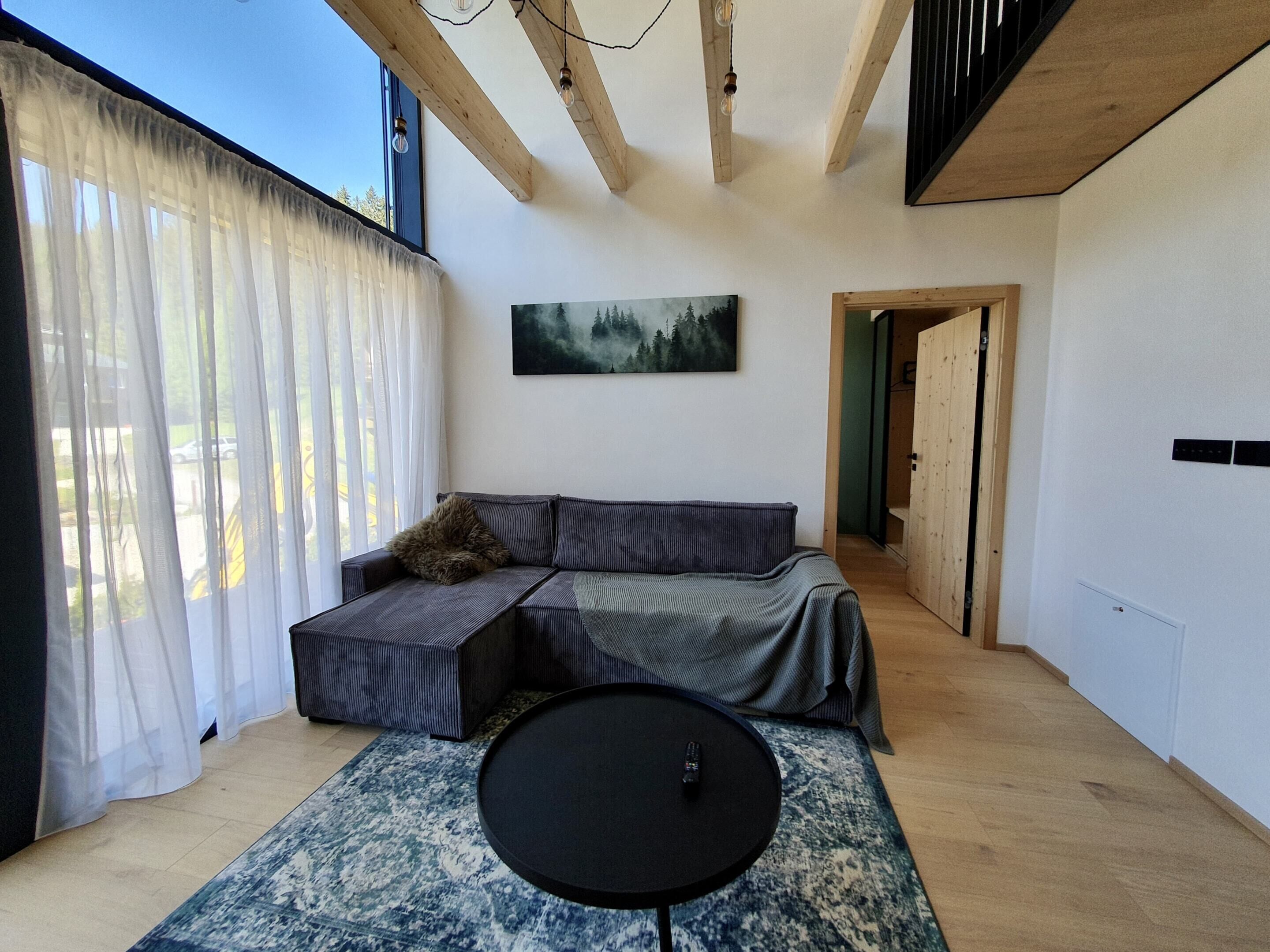A modern room with a sofa, a round table, and a painting on the wall.