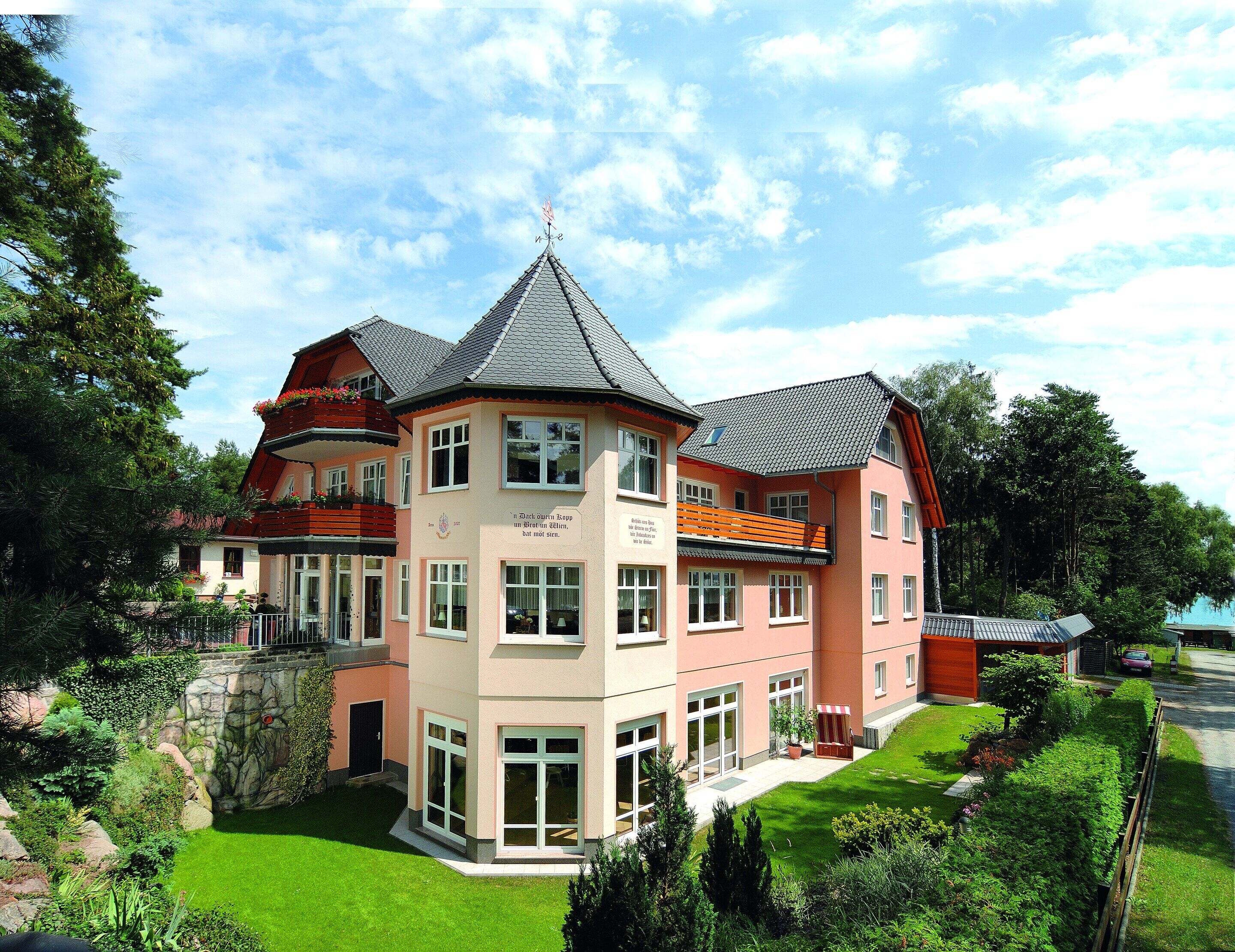 Ein mehrgeschossiges Gebäude mit einem zentralen Turm, großen Fenstern und einem gepflegten Garten.
