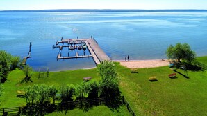 Un molo che si protende in un lago tranquillo, con imbarcazioni ormeggiate, circondato da aree erbose e alberi.