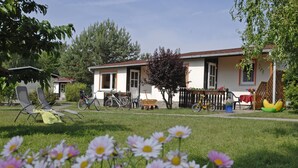 Una casa con un prato, una bicicletta e una sedia.