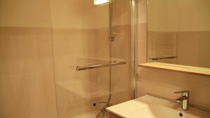 Ein Badezimmer mit Duschkabine aus Glas, einem Waschbecken mit Spiegel darüber und einer Holzausstattung.