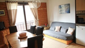 Ein gemütliches Zimmer mit einem Holzesstisch, Stühlen, einer Couch und einer Küchenzeile.