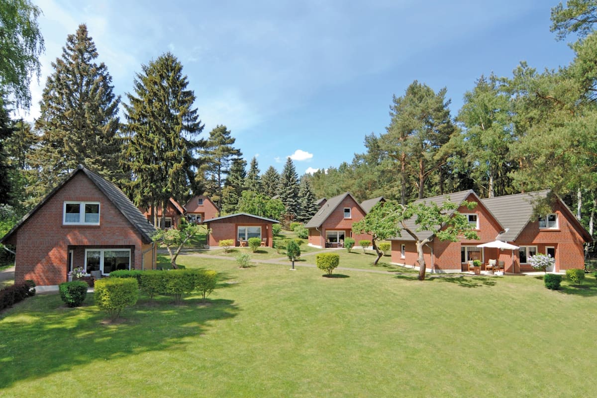 Une rangée de maisons en briques, avec une pelouse bien entretenue et des arbres en arrière-plan.