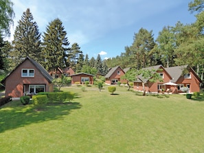 A row of brick houses with a well-maintained lawn and trees in the background. - Seepark Heidenholz, Plau am See (Plau am See)