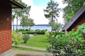 A brick building with a number '15' on the wall, a grassy yard, and a view of a lake. - Seepark Heidenholz, Plau am See (Plau am See)