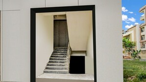 A modern building with a central staircase leading to an upper floor. - Townhouse Near Narsingi Manikonda (Hyderabad)