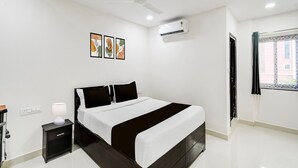 A modern bedroom with a bed, bedside table, lamp, ceiling fan, air conditioning unit, and artwork on the wall. - Townhouse Near Narsingi Manikonda (Hyderabad)