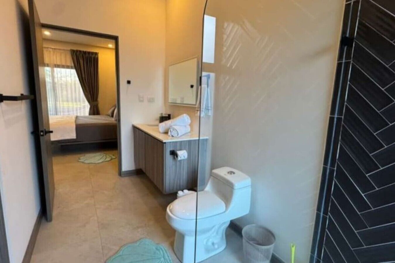 Una habitación de hotel con cama, baño con inodoro, lavabo y espejo.