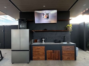 A modern outdoor kitchen with a built-in refrigerator, a coffee maker, and a sink. - Casa Rouge Private Retreat in Paradise (Carrillo)