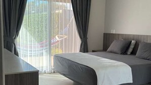 Une chambre d’hôtel moderne, équipée d’un lit, d’un bureau et offrant une vue sur l’extérieur.