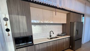 Une cuisine moderne dotée d’un four à micro-ondes encastré, d’appareils électroménagers en acier inoxydable et d’un grand réfrigérateur.