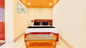 Un dormitorio con cama, ventilador de techo, mesita de noche y ventana con persianas.