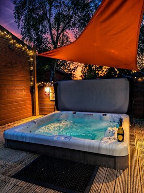 A hot tub with a canopy, surrounded by wooden decking and string lights. - Alfie's Place. Felmoor Park (Felmoor Park)