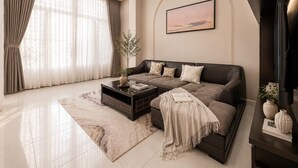 A modern living room with a sofa, coffee table, and a painting on the wall. - Group Stay in Central Saigon_ 6 Bedrooms + Private Baths (Thành phố Hồ Chí Minh)