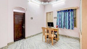 A room with a marble floor, a wooden desk with a computer, two chairs, a door, and a window with patterned curtains. - Hotel O Buckingham Canal Vijayawada (Vijayawada)