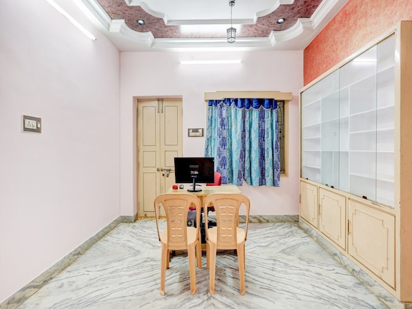 A room with a desk, two chairs, a computer, a window with curtains, a wardrobe, and a door.