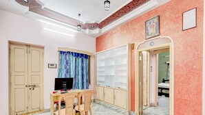 A room with a desk, chairs, a television, a bookshelf, and a door leading to another room. - Hotel O Buckingham Canal Vijayawada (Vijayawada)