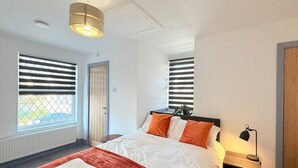 Ett hotellrum med en säng, två sängbord, en lampa och ett fönster med persienner.