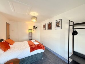 A hotel room with a bed, a desk, a chair, a wardrobe, and a wall-mounted shelf. - 7 Spacious 1Bed House Sleeps 3 Secure Parking WiFi (Cleethorpes)