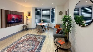A modern living room with a TV, dining area, and a large mirror. - 5 Spacious 2-Bed Flat Sleeps 4 Secure Parking WiFi (Cleethorpes)