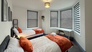 A room with two beds, a desk, and a hanging plant. - 5 Spacious 2-Bed Flat Sleeps 4 Secure Parking WiFi (Cleethorpes)