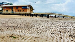 A beach with a wooden building and a bridge. - 6 Spacious 1-Bed Flat Sleeps 3 Secure Parking WiFi (Cleethorpes)