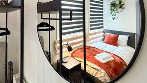 A circular mirror reflecting a bedroom with a bed, bedside table, and a hanging plant. - 6 Spacious 1-Bed Flat Sleeps 3 Secure Parking WiFi (Cleethorpes)