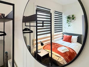 A circular mirror reflecting a bedroom with a bed, bedside table, and a hanging plant. - 6 Spacious 1-Bed Flat Sleeps 3 Secure Parking WiFi (Cleethorpes)