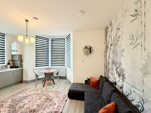A modern living room with a sofa, a dining table, and a kitchen area. - 2 Spacious 1-Bed Flat Sleeps 3 Secure Parking WiFi (Cleethorpes)