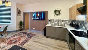 A modern kitchen with a TV, wooden cabinets, and a patterned backsplash. - 1 Spacious 1-Bed Flat Sleeps 3 Secure Parking WiFi (Cleethorpes)